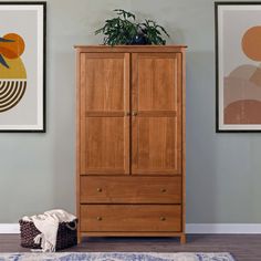 a tall wooden cabinet sitting next to a wall with pictures on the wall behind it