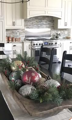 a kitchen decorated for christmas with ornaments and greenery on the counter top in front of an oven