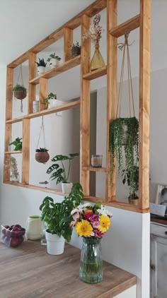 a vase filled with flowers sitting on top of a wooden table next to a mirror