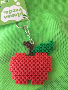 an apple shaped keychain made out of legos on a green surface with a card