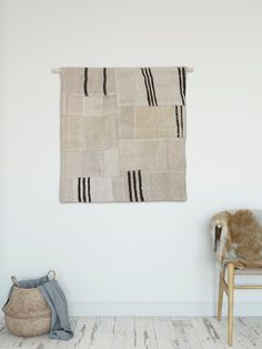 a chair sitting in front of a white wall with a rug hanging on the wall