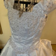 a white wedding dress is displayed on a rack in front of a wall and mirror