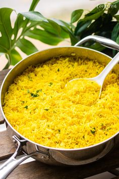 a pan filled with yellow rice on top of a wooden table