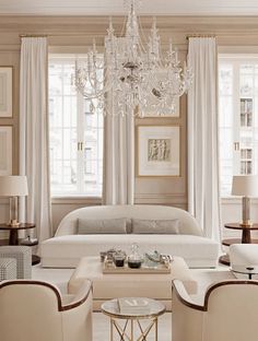 a living room filled with furniture and a chandelier hanging over it's windows