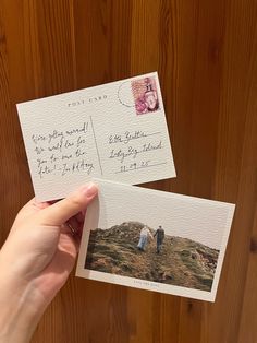 someone holding up two postcards with an envelope