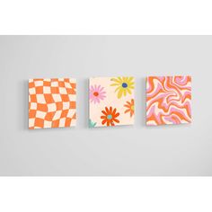 three square paintings hanging on the wall with different patterns and colors, each featuring flowers