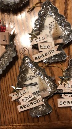 christmas tree ornaments made out of aluminum foil with words on them, hanging from the ceiling