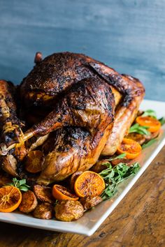 a roasted turkey on a platter with oranges and herbs