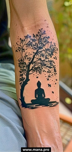 a person sitting under a tree with a tattoo on their leg