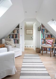 an attic living room with white furniture and bookshelves