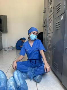 a woman in scrubs sitting on the floor next to lockers