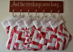 several red and white quilts hanging on a wall next to a sign that says and the stockings were hung