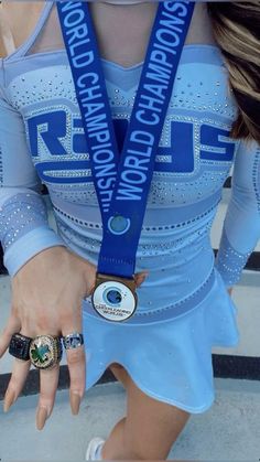 a woman in a blue cheer uniform holding onto a medal