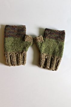 two knitted mittens sitting next to each other on a white surface, one with green and brown stripes