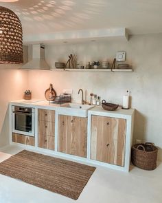 a kitchen with white walls and wooden cabinetry on the counter top, along with a rug in front of it