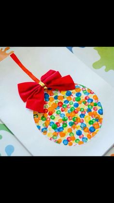 an ornament with a red bow is on top of a white paper bag