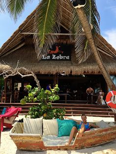 a man laying on top of a couch under a palm tree next to a building