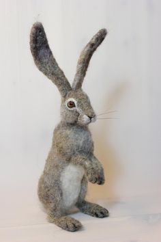 a stuffed rabbit sitting on its hind legs with one eye open and the other half closed