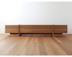 a wooden bench sitting on top of a hard wood floor next to a white wall