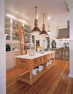 a kitchen with white walls and wooden floors, two ladders hanging from the ceiling