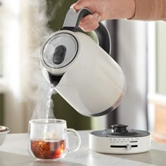 a person is pouring tea into a cup with steam coming from the top and bottom