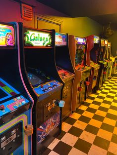 several video game machines lined up in a row on a checkered floor with yellow and black tiles