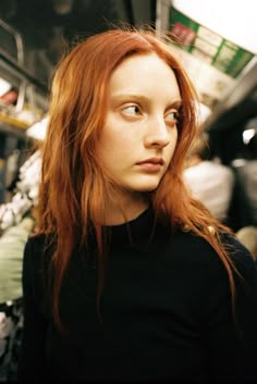 a woman with red hair is looking at the camera