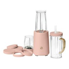 the blender is pink with gold trimmings and two cups next to it