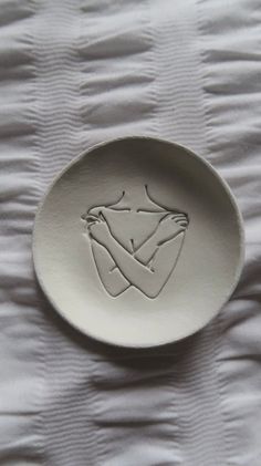 a white plate with an image of a woman's torso on it, sitting on a bed