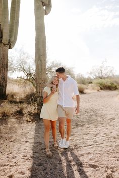 a man and woman standing next to each other in front of a saguada