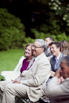 a group of people sitting next to each other on top of a grass covered field