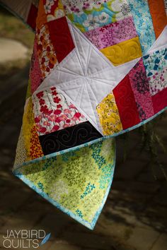 a colorful quilt hanging from the side of a tree