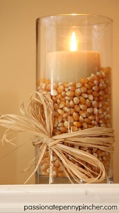 a glass jar filled with corn and a lit candle