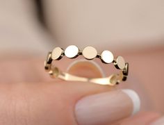 a woman's hand holding a gold ring with three circles on it, and the middle