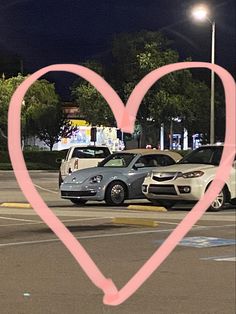 two cars parked next to each other in a parking lot with a heart drawn on it