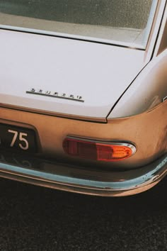 the back end of an old car parked in a parking lot