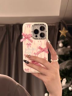 a woman holding up her phone case with pink bows on the front and back cover