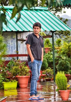 a man standing in the rain next to potted plants