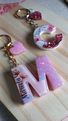 the letter m is made out of plastic and has pink glitter on it, along with other items