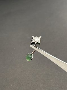 a pair of green earrings sitting on top of a piece of metal with a star design