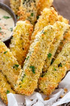 some fried zucchini sticks with dipping sauce on the side