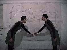 two people holding hands in front of a drawing on the wall with white paper behind them