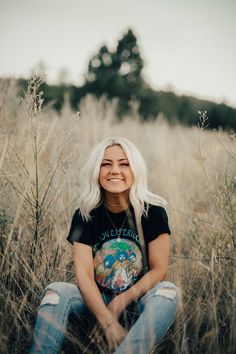 a woman sitting in tall grass smiling at the camera