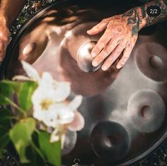 a man with his hand on the top of a large metal pan that has flowers growing out of it