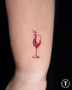 a small wine glass tattoo on the right side of the leg, which has a red liquid coming out of it