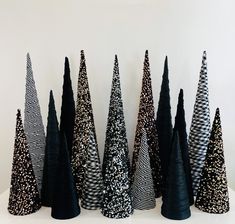 black and white christmas trees are lined up on a table with silver glittered decorations