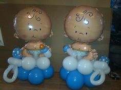 two little baby dolls sitting on top of blue and white balloons in front of a cardboard box