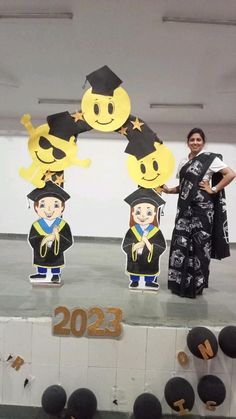 two people standing on top of a stage with paper cutouts in the shape of smiley faces