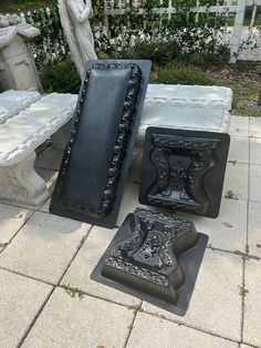 three black and white benches sitting next to each other on a sidewalk in front of a statue