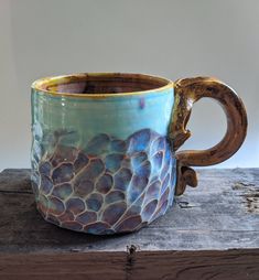 a blue and brown coffee cup sitting on top of a wooden table